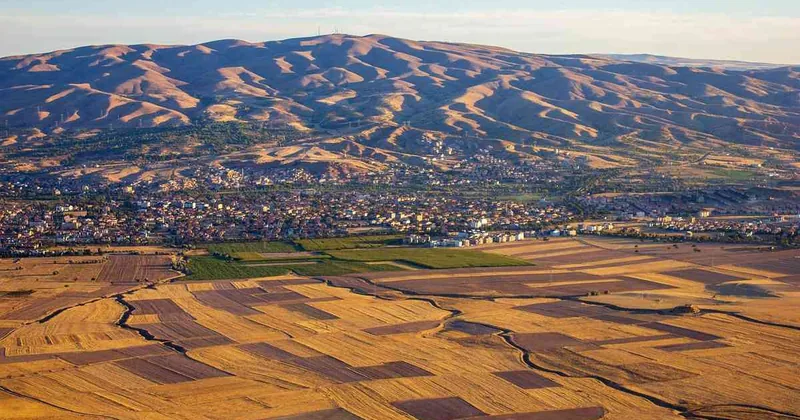 Vue aérienne de paysages vallonnés avec des zones agricoles et une ville en arrière-plan